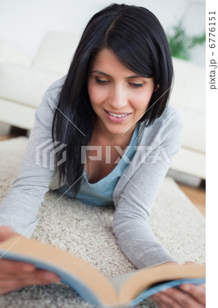 Smiling woman reading a book while lying on the floor Smiling woman reading a book while lying on the floor 6776151