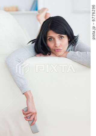 Sad woman on a sofa holding a television remote 6776296