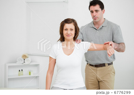 Doctor examining the shoulder of his patient while holding his a Doctor examining the shoulder of his patient while holding his a 6776299