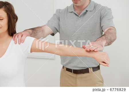 Woman sitting while a doctor is examining her arm 6776829