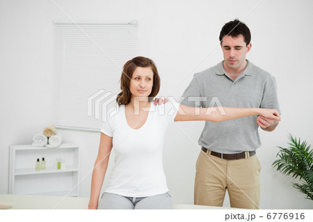 Serious practitioner extending the arm of a patient 6776916