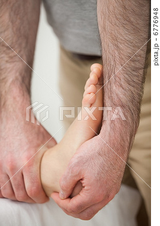 Doctor making a joint mobilisation on the ankle of a woman 6776948