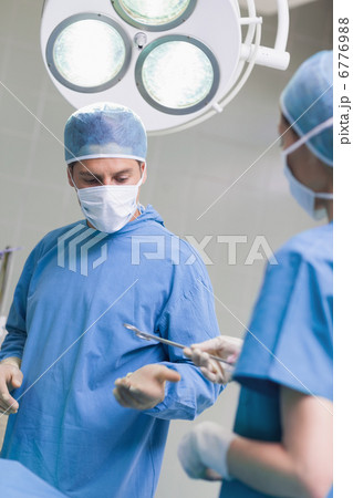 Nurse giving surgical scissors to a doctor Nurse giving surgical scissors to a doctor 6776988