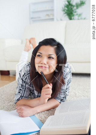 Thinking woman lying on the floor with a book and a notebook Thinking woman lying on the floor with a book and a notebook 6777038