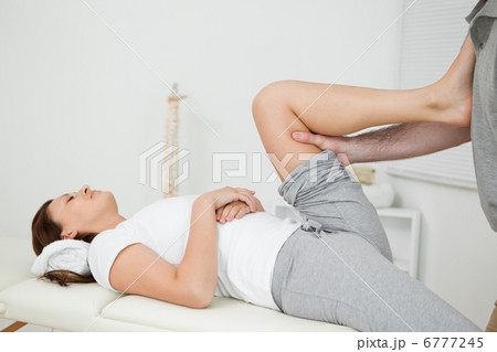 Woman putting her foot on the chest of her doctor while stretchi 6777245