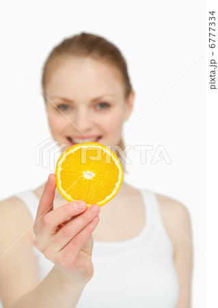 Woman presenting an orange slice while smiling 6777334
