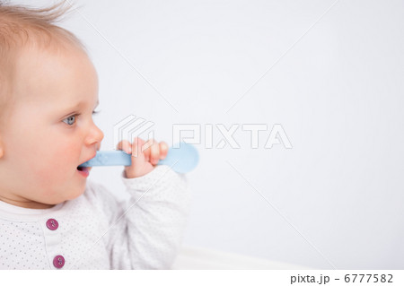 Cute baby biting a blue spoon Cute baby biting a blue spoon 6777582