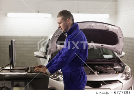 Mechanic standing while looking at a computer Mechanic standing while looking at a computer 6777893