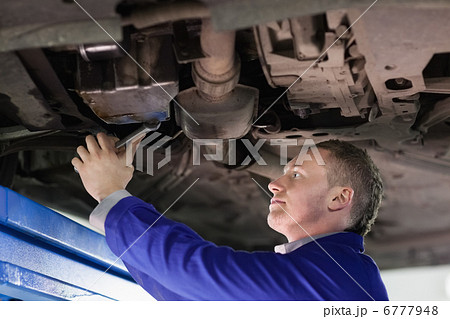 Mechanic repairing the below of a car 6777948