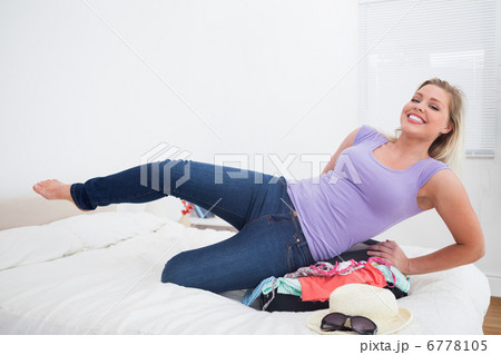 Smiling woman trying to close her suitcase 6778105