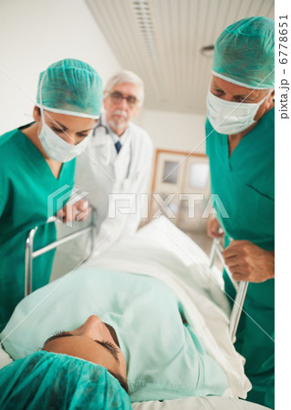 Patient lying on a medical bed next to doctors Patient lying on a medical bed next to doctors 6778651