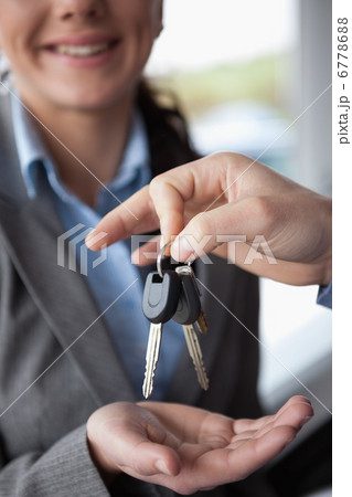 Hand holding keys over the hand of a woman 6778688