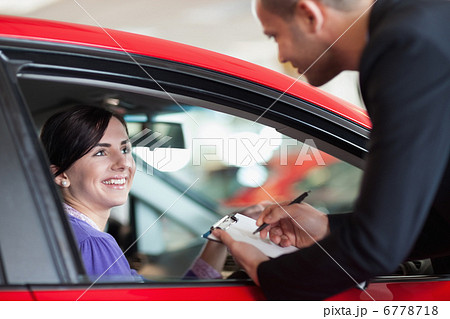 Woman in a car talking with a salesman 6778718