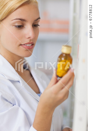 Blonde pharmacist looking at a drug bottle Blonde pharmacist looking at a drug bottle 6778812