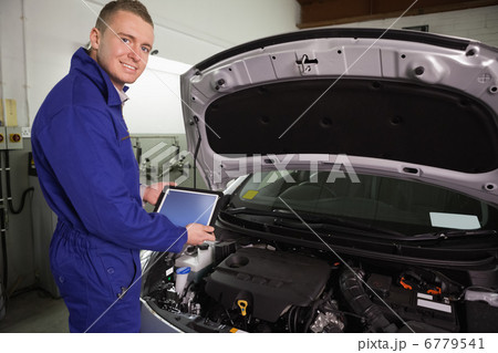 Mechanic looking at camera while holding a tablet computer 6779541