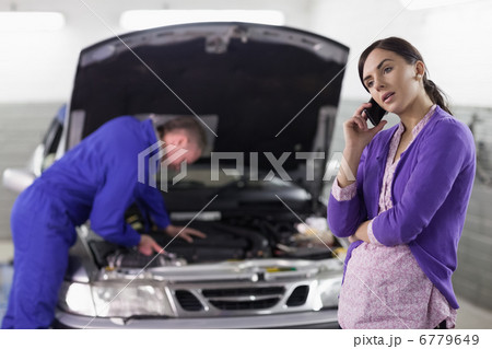 Woman calling next to a mechanic Woman calling next to a mechanic 6779649