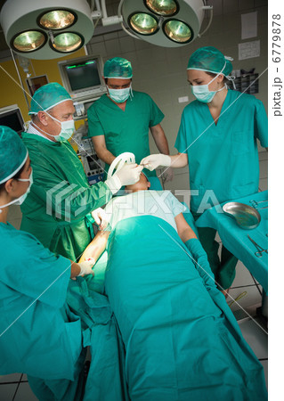 Surgeon working on the arm of a patient with a team of surgeons 6779878