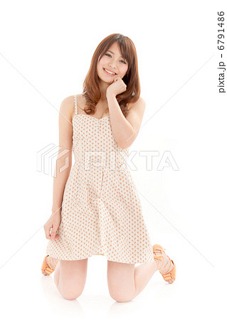 膝立ちでキュートなポーズを取る可愛らしい女の子の写真素材