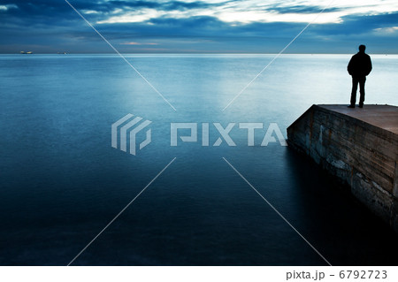 Man is standing on a jetty looking the sunset 6792723