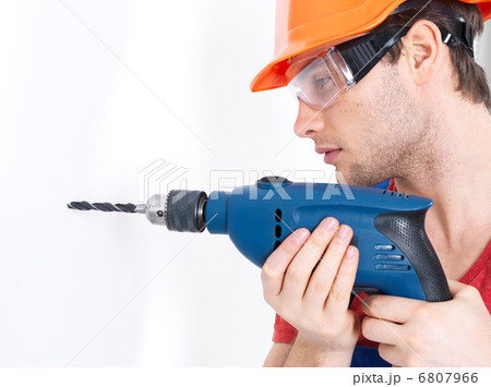 A man drilling a hole in the wall. 6807966