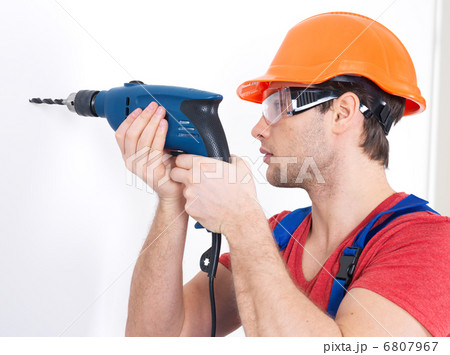 A man drilling a hole in the wall. 6807967