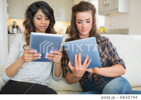Two women holding and looking at tablet computers 6830794