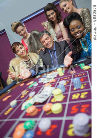 Man surrounded by women at roulette table 6830858