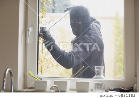 Burglar breaking a kitchen window Burglar breaking a kitchen window 6831182