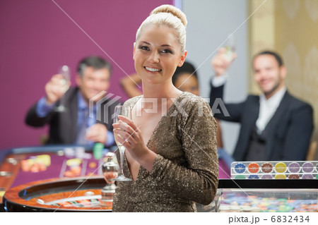 Woman holding champagne glass as people are cheering behind her Woman holding champagne glass as people are cheering behind her 6832434