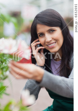 Smiling florist touching a flower and making a call 6832691