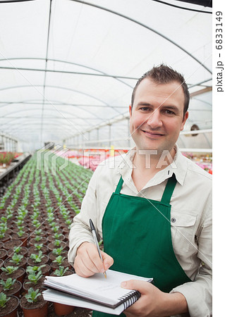 Smiling man taking notes in greenhouse 6833149