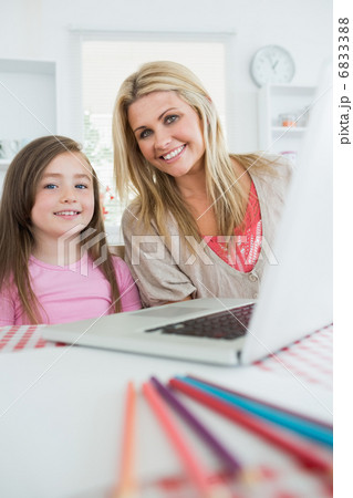 Mother and girl are smiling at the kitchen 6833388