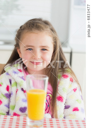 Little girl sitting while smiling with glass of orange juice Little girl sitting while smiling with glass of orange juice 6833477