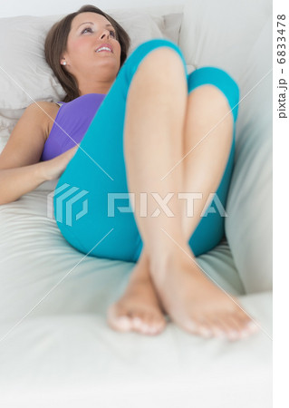 Happy woman lying on sofa looking away 6833478