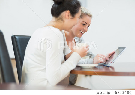 Smiling woman sitting while holding a tablet pc Smiling woman sitting while holding a tablet pc 6833480