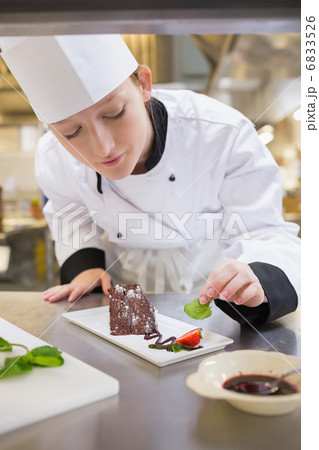 Female chef putting mint with cake 6833526