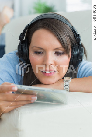 Woman listening music and looking at cd on sofa Woman listening music and looking at cd on sofa 6834098
