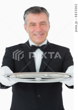 Waiter looking at the camera while holding a silver tray Waiter looking at the camera while holding a silver tray 6835002