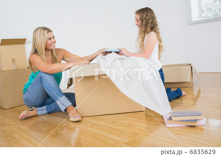 Mother and daughter opening cartons 6835629