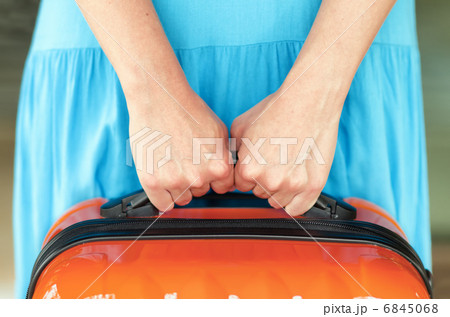 Woman in blue dress holds orange suitcase in hands Woman in blue dress holds orange suitcase in hands 6845068