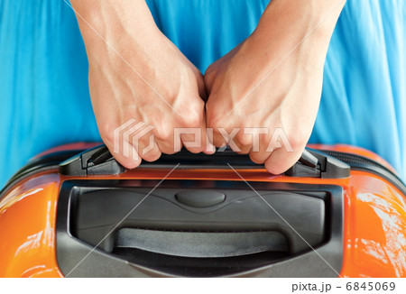 Woman in blue dress holds orange suitcase in hands Woman in blue dress holds orange suitcase in hands 6845069