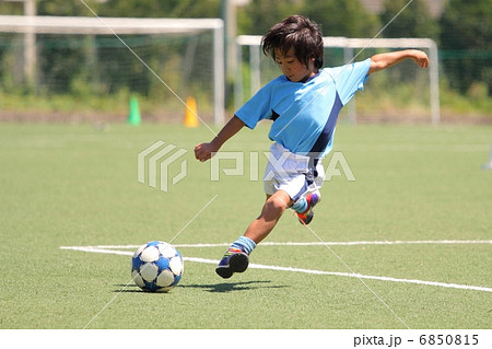 ユニフォームを着たサッカー少年のシュートシーンの写真素材