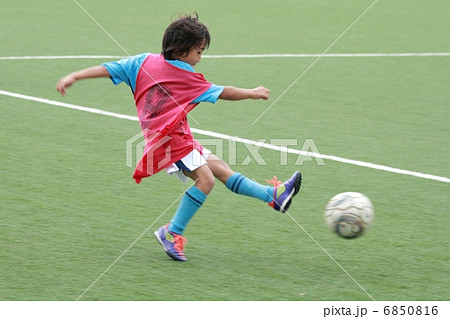 ユニフォームを着たサッカー少年のシュートシーンの写真素材