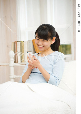 ベッドでスマートフォンを楽しむ女性 6889856
