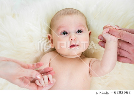 baby girl holding parental hands lying on fur bed baby girl holding parental hands lying on fur bed 6892968