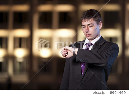 Handsome businessman watching time at night city in the backgrou Handsome businessman watching time at night city in the backgrou 6904469