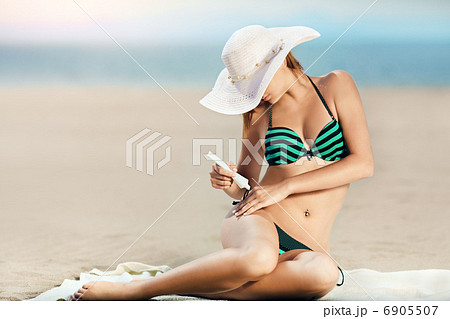 Portrait of woman taking skincare with sunscreen lotion at beach 6905507