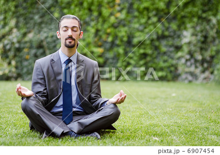 Young businessman meditating in the garden 6907454
