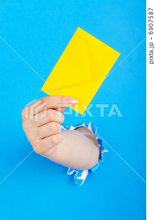 Hand holding paper envelope from hole Hand holding paper envelope from hole 6907587