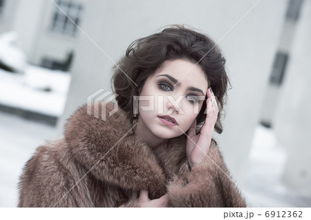 Femininity. Portrait of Sophisticated Young Brunette in Brown Fur Coat Outdoors Femininity. Portrait of Sophisticated Young Brunette in Brown Fur Coat Outdoors 6912362